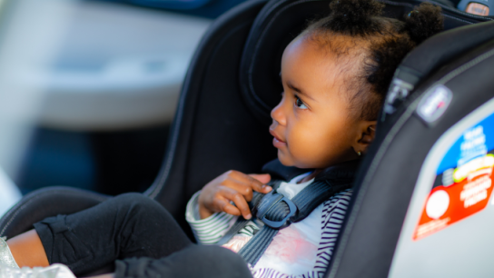 African American baby sitting in child restraint system 