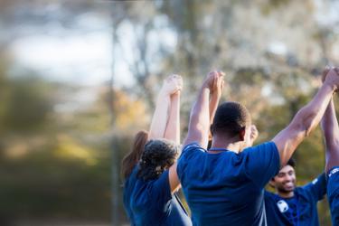 Team wearing blue uniforms holding hands