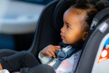 African American baby sitting in child restraint system 